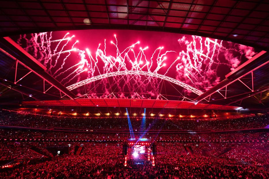 Fireworks exploding over a stadium filled with a crowd.