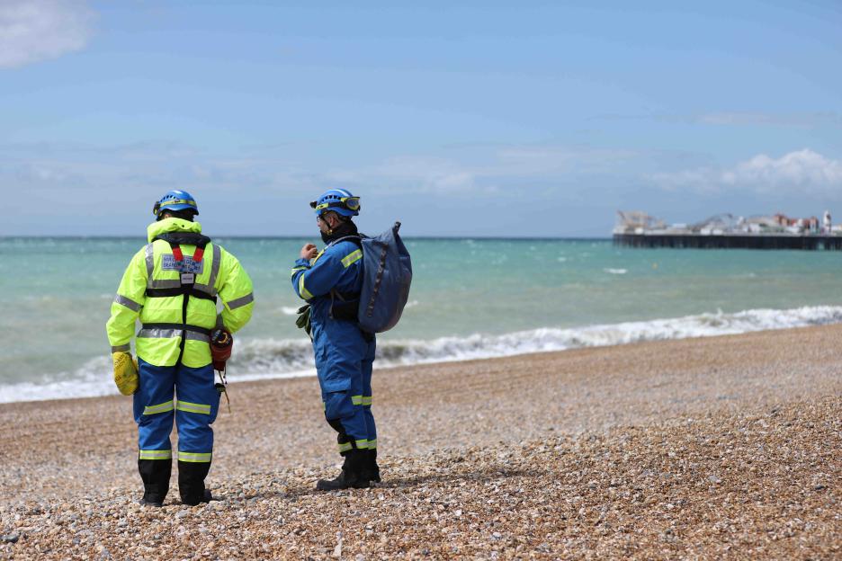 Two members of a search and rescue team stand on Brighton beach.