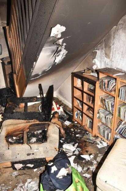 The scene of a fire showing a damaged chair, stairs, and bookshelves in a room.