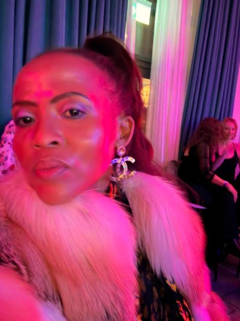 A woman wearing a white fur shawl and large Chanel earrings.