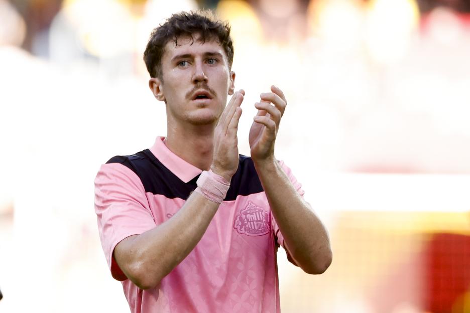A Sunderland AFC player in a pink and black jersey claps with a serious expression.