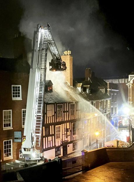 Firefighters battling a blaze at a historic 16th-century building at night.