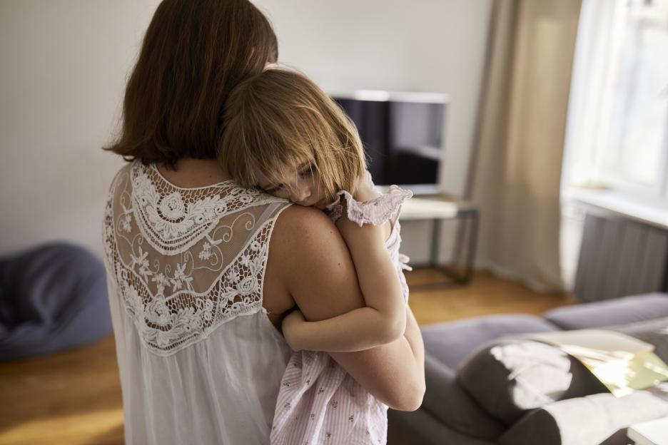 Mother carrying her tired daughter at home.