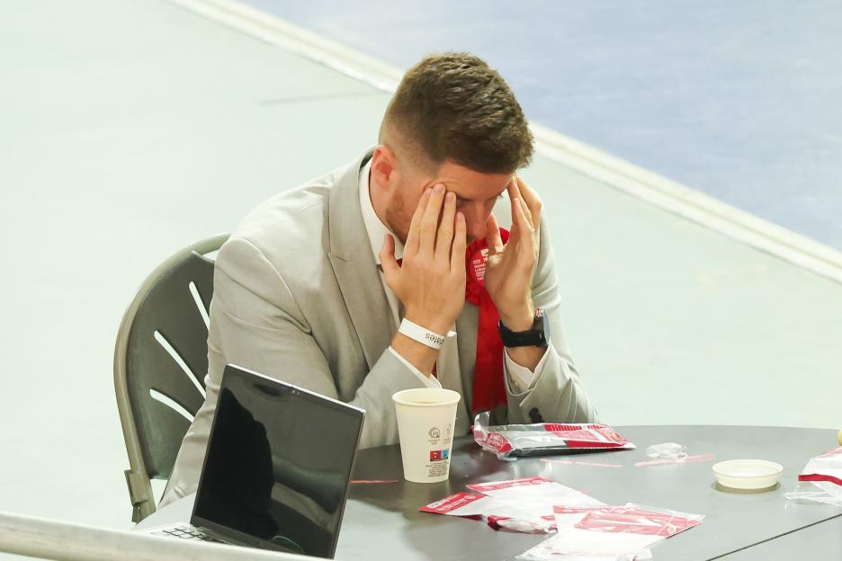 Chris Carter, Labour Candidate for Casnewydd Islwyn, with his hands on his face, sitting at a table with a laptop, paper cup, and red campaign materials.