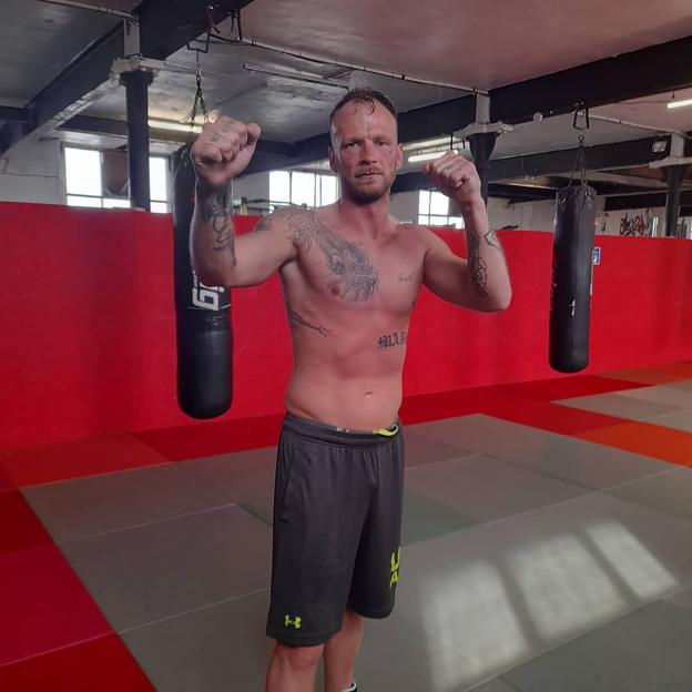 Callum Kerr, a bare-knuckle boxer, posing in a boxing gym.