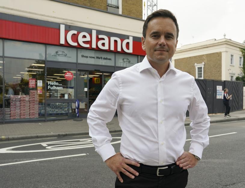 Richard Walker, Iceland's boss, standing in front of an Iceland supermarket.