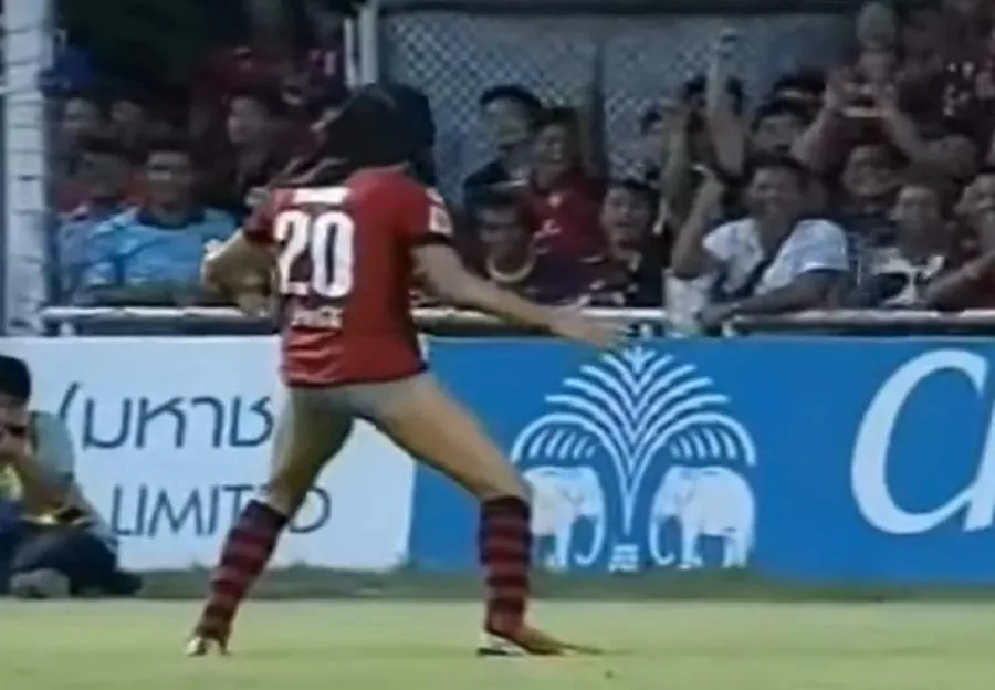 Football player with his shorts pulled over his head, celebrating in front of a cheering crowd.