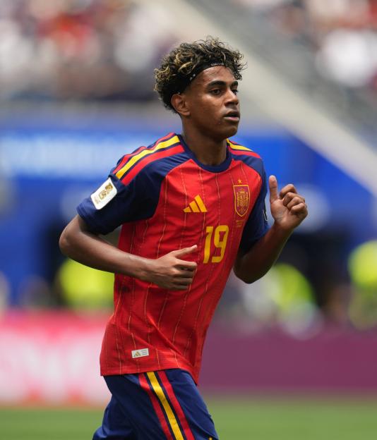 A male soccer player in a red and blue uniform with number 19 running on the field.