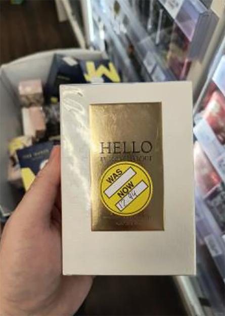 Hand holding a "HELLO" product with a yellow sticker showing "WAS" and "NOW 12.99".