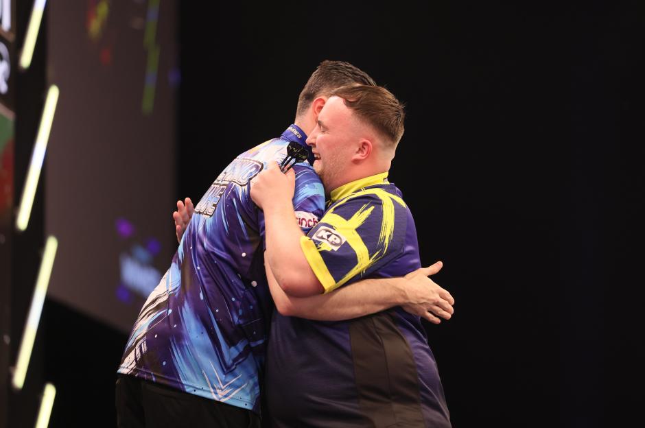 Luke Humphries and Luke Littler embrace after their darts match.