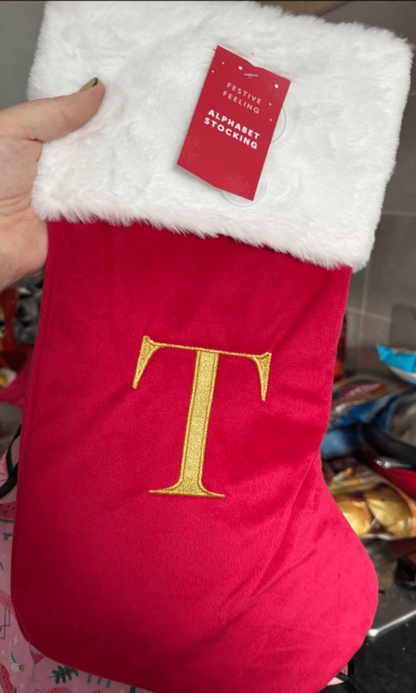 Red Christmas stocking with white faux fur cuff and a gold embroidered letter T.