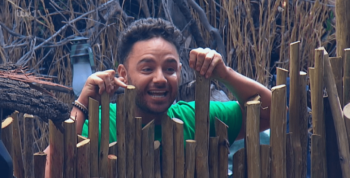 Ryan Thomas laughing while peering over a wooden fence.