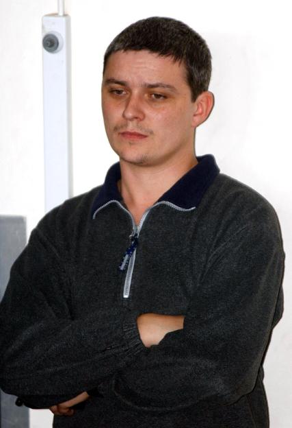 Ian Huntley looking down with his arms crossed.