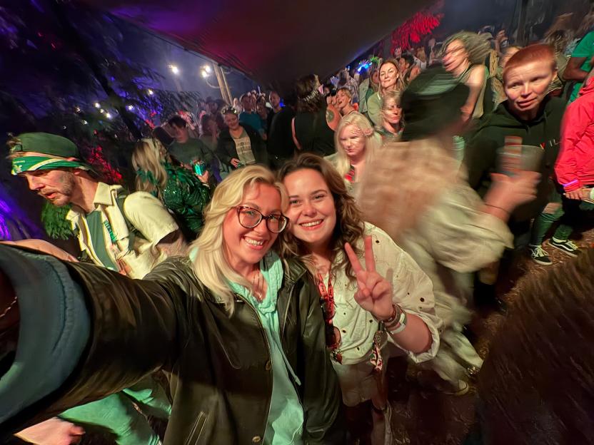 Two women posing for a selfie in a crowded, dimly lit indoor space.