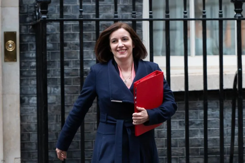 Bridget Phillipson smiling while holding a red folder in Downing Street, London.