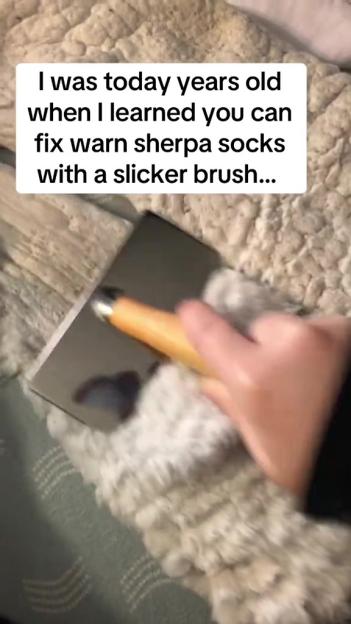 A person brushing a white sherpa sock with a slicker brush.