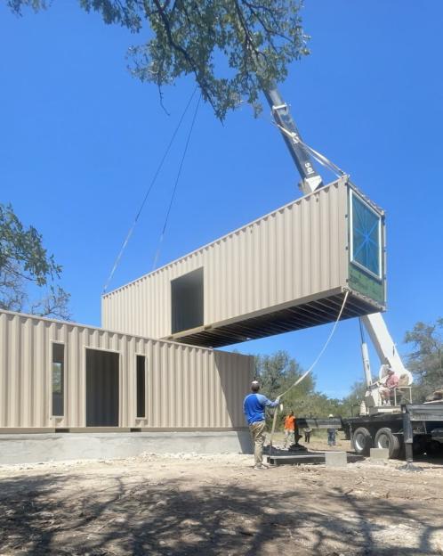 Construction of a shipping container home using a crane to position one container above another.