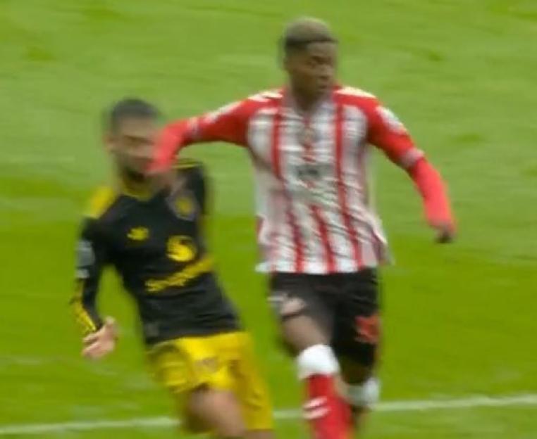 A soccer player in a black and yellow uniform being pushed away by a player in a red and white striped uniform.
