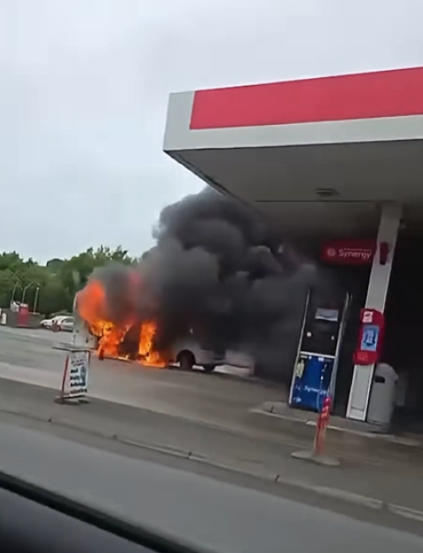 Campervan engulfed in flames at a petrol station forecourt.