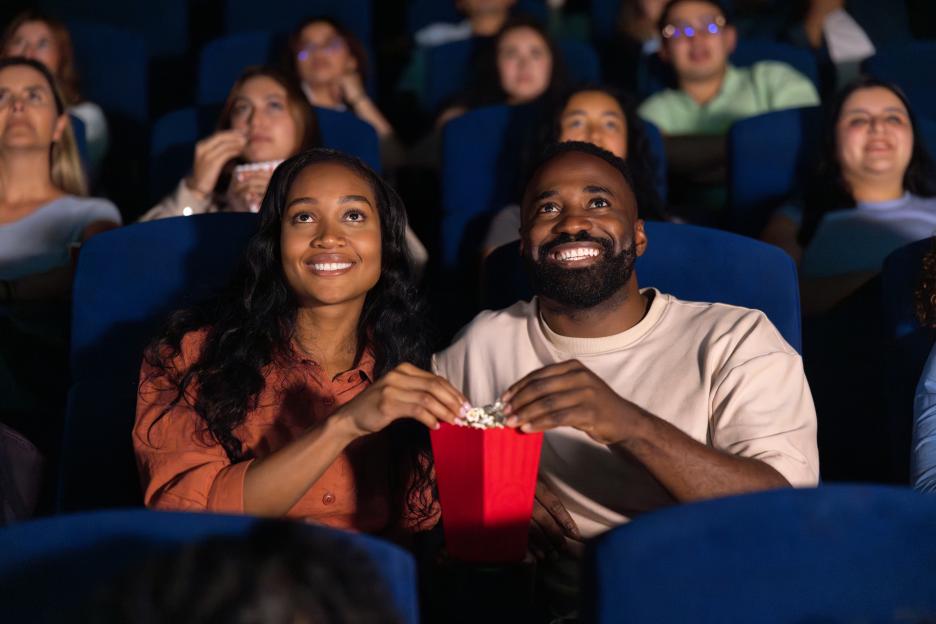 Loving couple watching a movie at the theatre and eating popcorn