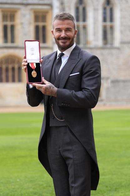 Sir David Beckham made a Knight Bachelor holding his medal at Windsor Castle.