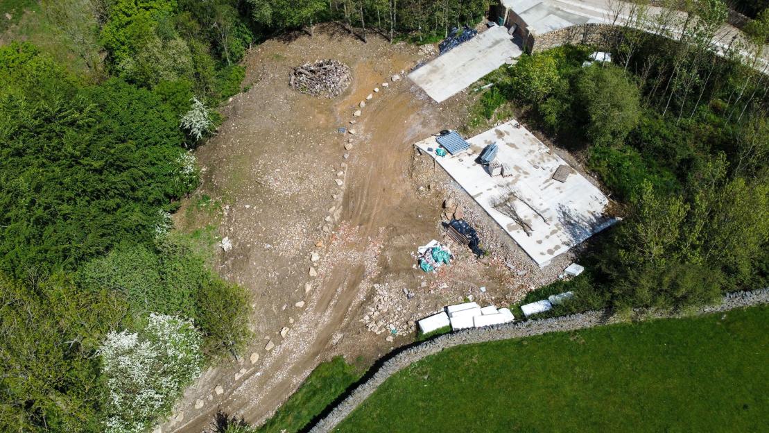 Aerial view of Jacobs Hill Farm with concrete pads and groundworks for holiday homes in a wooded area.