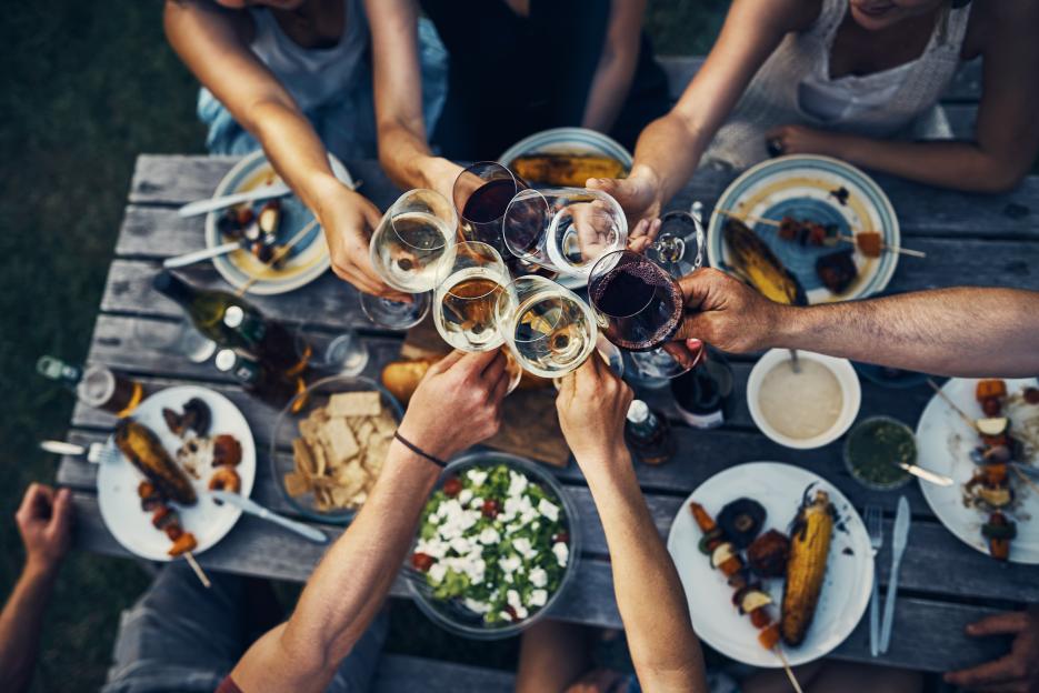 A group of friends make a toast with wine glasses over dinner.