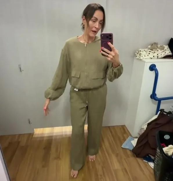 Woman in a changing room wearing a khaki green jumpsuit.