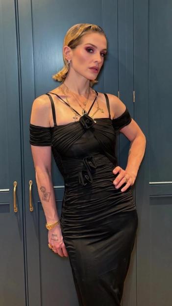Kelly Osbourne in a body-hugging black dress and slicked-back hair.