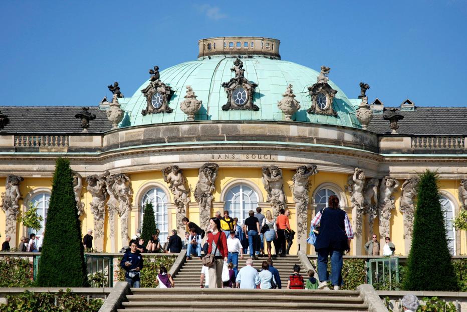 Sanssouci Palace in Potsdam, Germany, with tourists on the steps.
