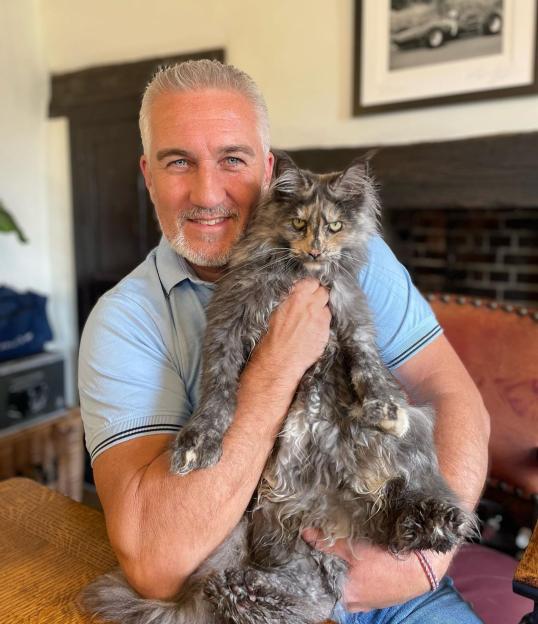 Paul Hollywood holding a large fluffy gray and orange cat.