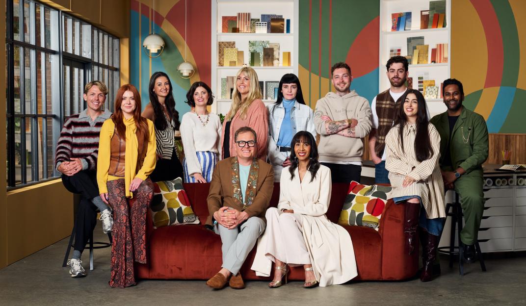 Cast members for Alan Carr's Interior Design Masters, with Alan Carr seated on a red sofa.