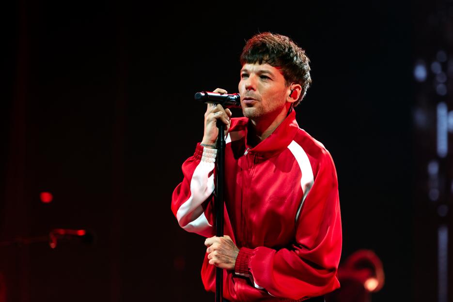 Louis Tomlinson performing onstage at a concert.