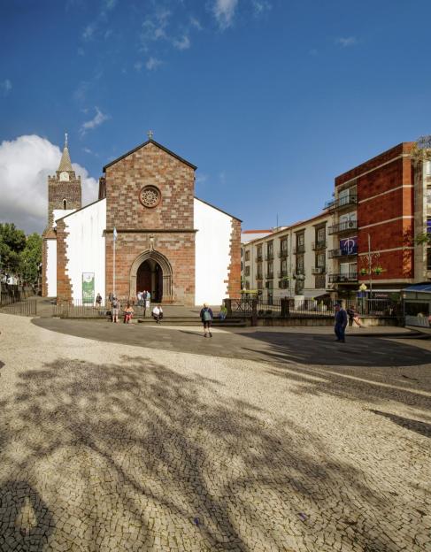 Funchal Cathedral in Portugal, with a cobblestone plaza in the foreground.