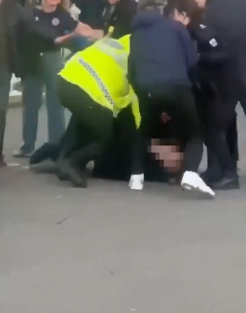 Police detaining a person on the ground.