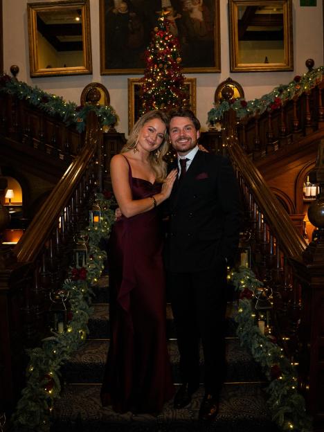 Tasha Amber Ghouri and a man in formal attire standing on a decorated staircase.
