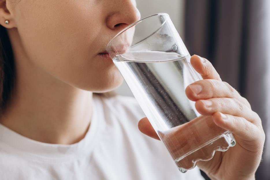 Young woman drinking water from a clear glass.