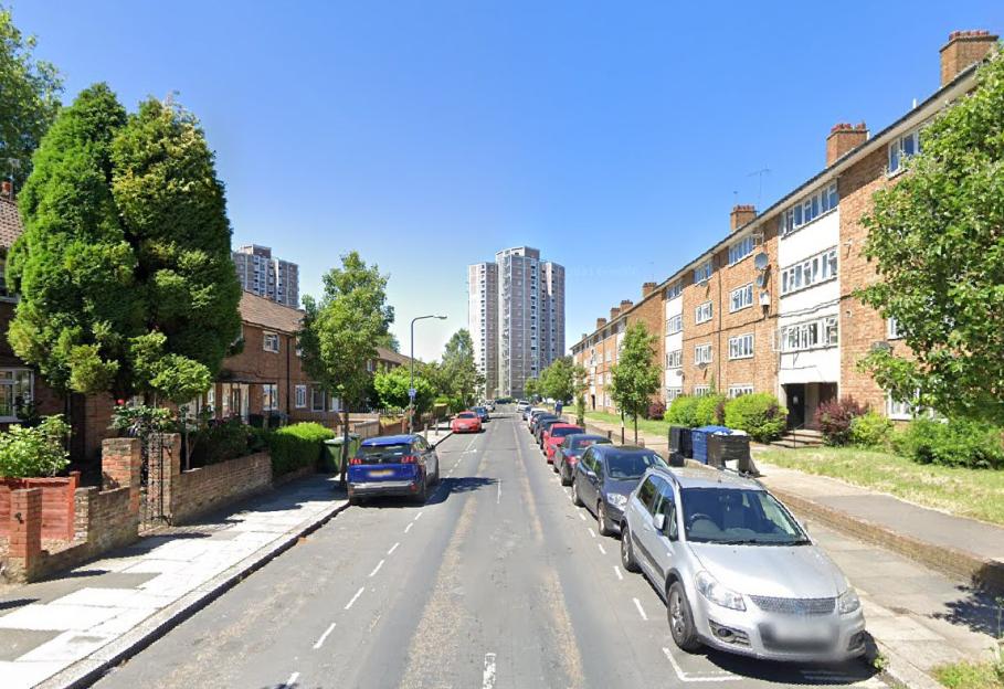 Street view of Lord Warwick Street in Woolwich, showing a residential street with parked cars, houses, and apartment buildings.