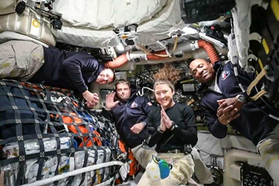 Four Artemis II crew members floating in a spacecraft, smiling at the camera.