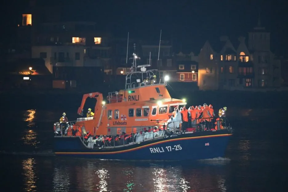 An RNLI lifeboat carrying migrants arriving in Gosport, England at night.