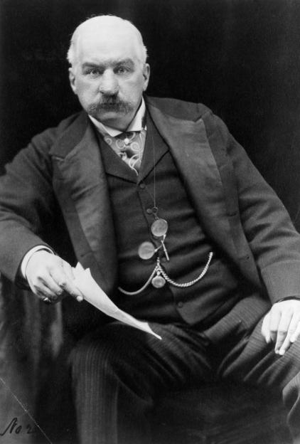 J.P. Morgan, an American financier, looking at the camera and holding a piece of paper.