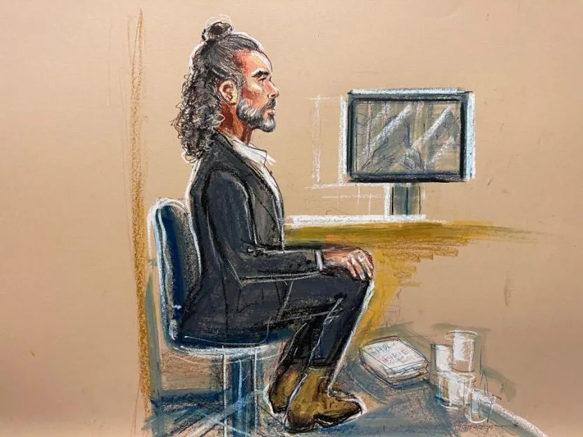 Court artist illustration of Russell Brand sitting in court watching a video monitor.