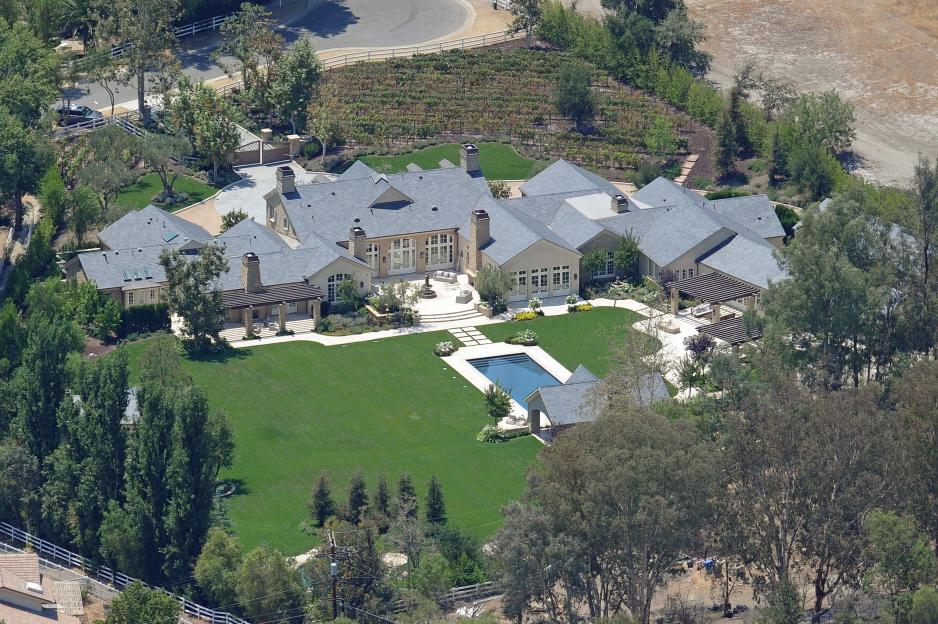 Aerial view of a sprawling mansion in Hidden Hills, California, with a large lawn and swimming pool.
