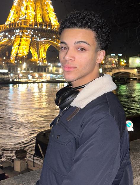Joshua Vaughan standing in front of the illuminated Eiffel Tower at night.