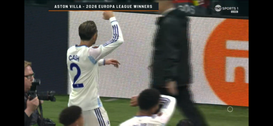 Soccer player Matty Cash wearing jersey number 2 with "CASH" on his back, raising his arms in celebration.
