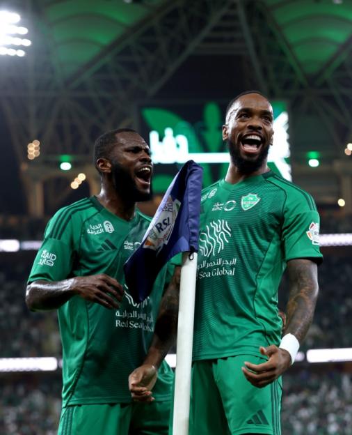 Two Saudi Pro League players celebrating on the field.