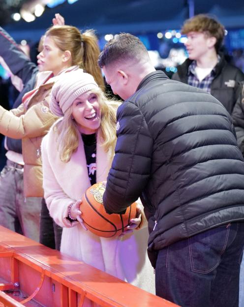 Kate Garraway smiling and holding a basketball while talking to a man.