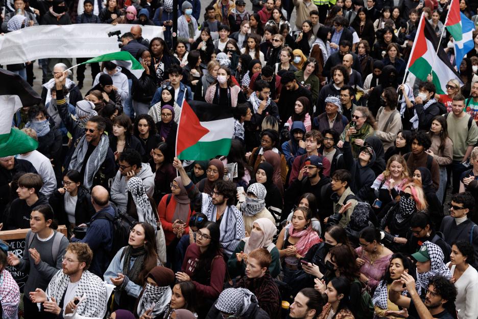 Large crowd of students at a pro-Palestine protest, with several Palestinian flags visible.