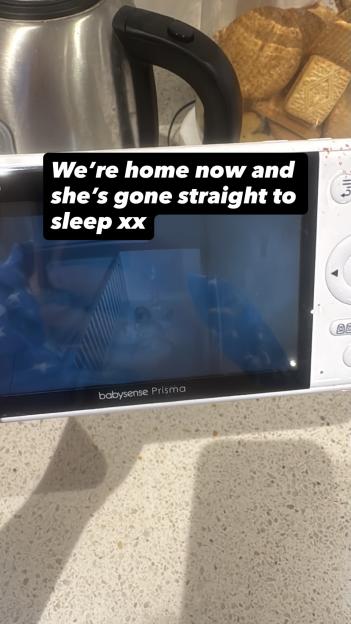 A baby monitor showing a baby asleep in a crib, with text "We're home now and she's gone straight to sleep xx" overlayed on the screen.