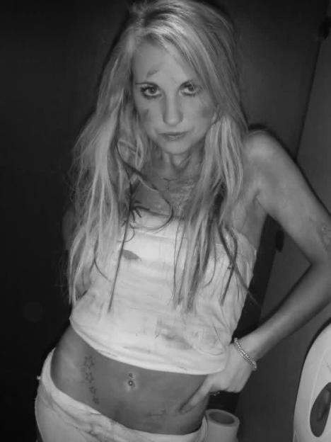 A young woman with smudged makeup and a star tattoo on her stomach.